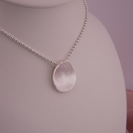 Handgefertigter Kettenanhänger Isola aus 925 Silber an einer Kugelkette, präsentiert auf einer eleganten Schmuckbüste.